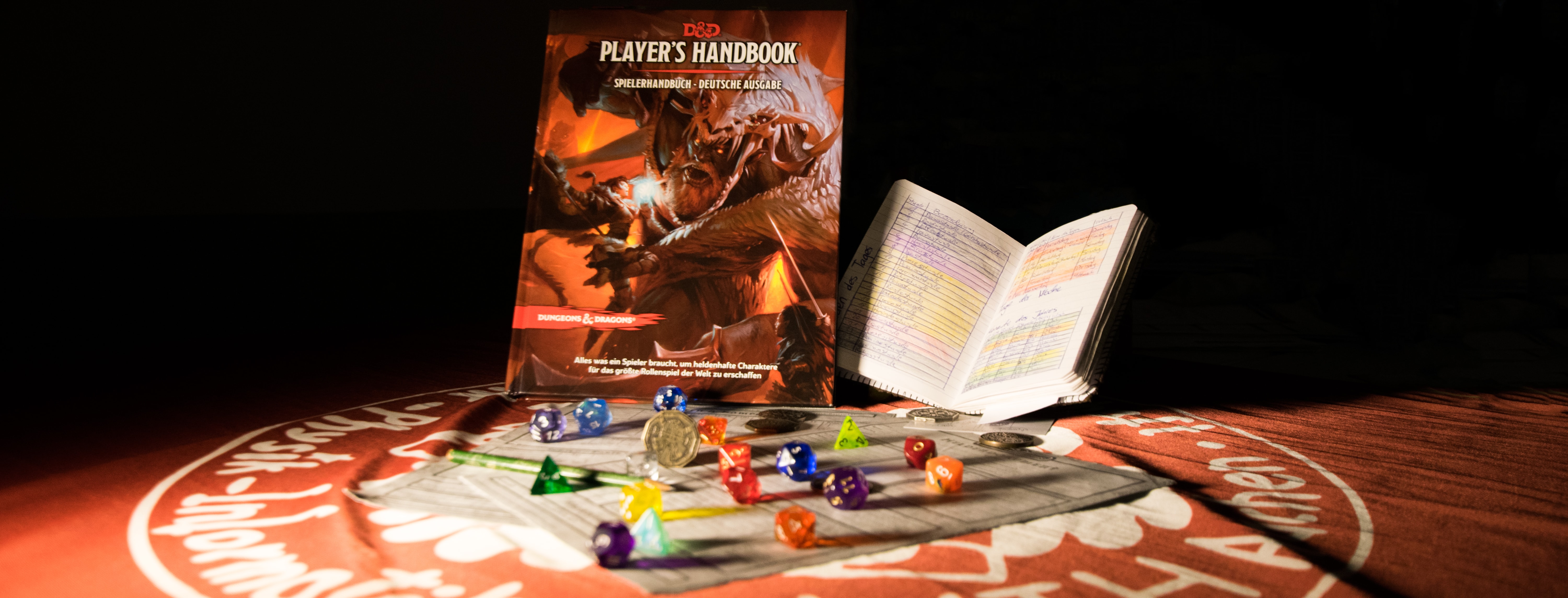 Symbolbild Rollenspielabend: Ein Regelwerk, Würfel und ein aufgeschlagenes Buch auf einem Tisch.